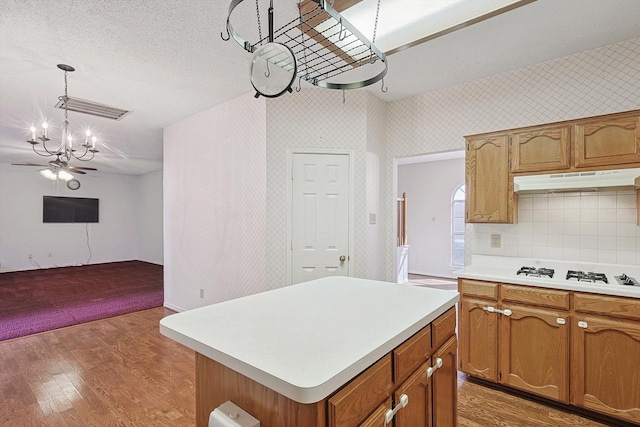 kitchen with a kitchen island, pendant lighting, hardwood / wood-style flooring, a notable chandelier, and white gas cooktop