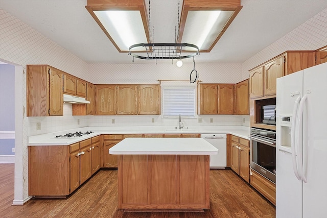 kitchen with dark hardwood / wood-style flooring, a center island, sink, and white appliances