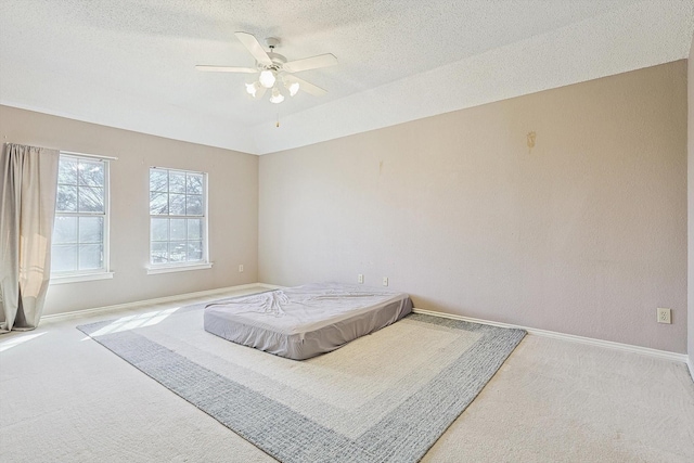 carpeted bedroom with ceiling fan and a textured ceiling