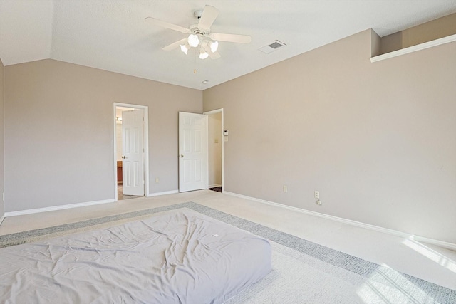 unfurnished bedroom with ceiling fan, light colored carpet, vaulted ceiling, and ensuite bath