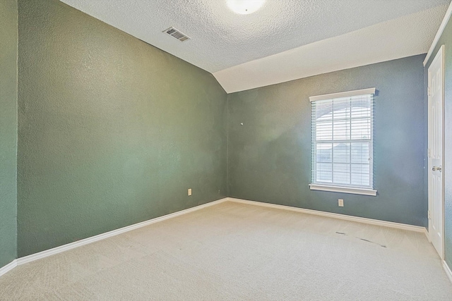 spare room featuring vaulted ceiling, a textured ceiling, and carpet flooring