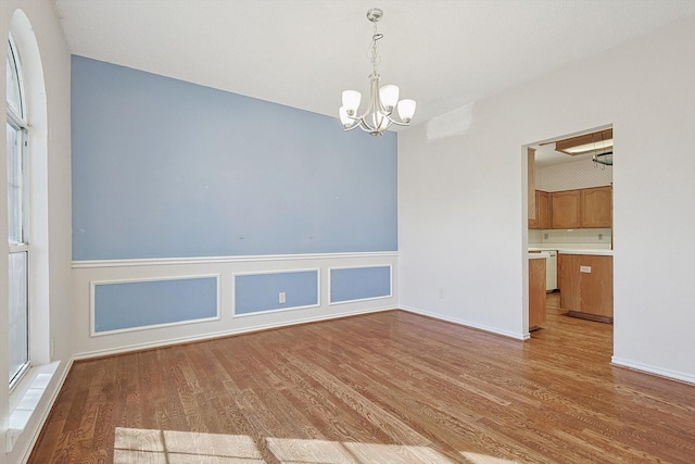 unfurnished room with an inviting chandelier and light hardwood / wood-style floors