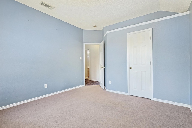 unfurnished bedroom with carpet, lofted ceiling, and a textured ceiling