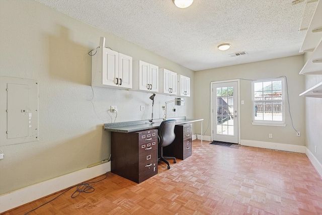 home office featuring light parquet floors, electric panel, and a textured ceiling