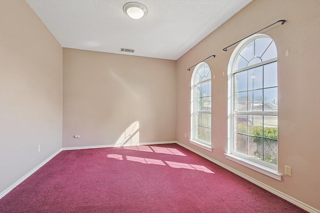 carpeted empty room with a textured ceiling