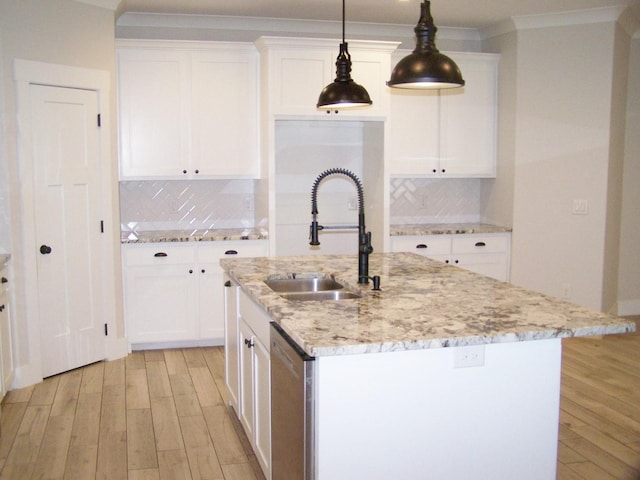 kitchen with white cabinetry, sink, light stone countertops, and an island with sink