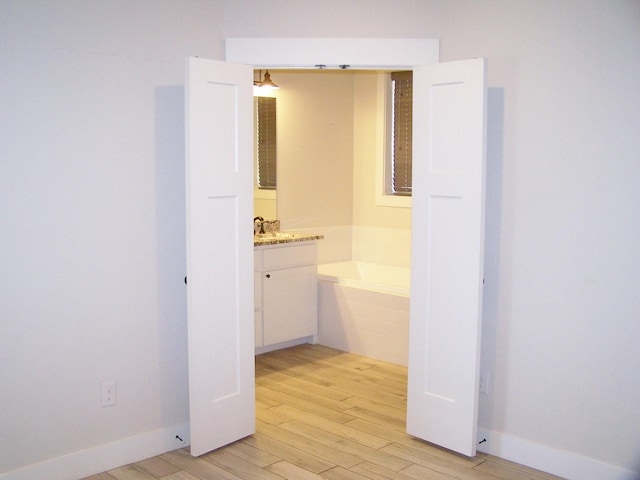 bathroom with vanity, a bath, and wood-type flooring