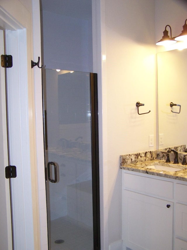 bathroom with vanity and a shower with door