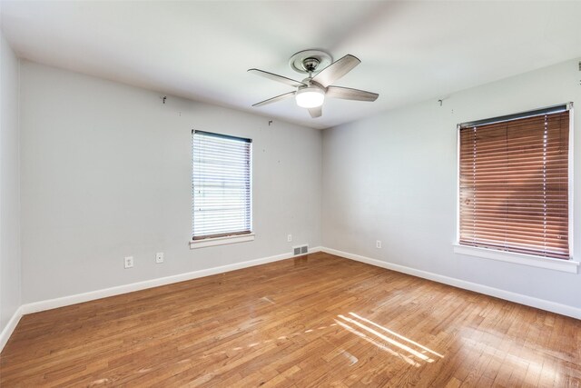 interior space with ceiling fan, wood finished floors, visible vents, and baseboards