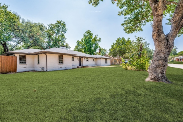 rear view of house with crawl space, fence, a lawn, and brick siding