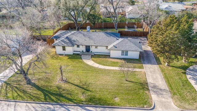 back of house with a fenced backyard, a trampoline, a lawn, and brick siding