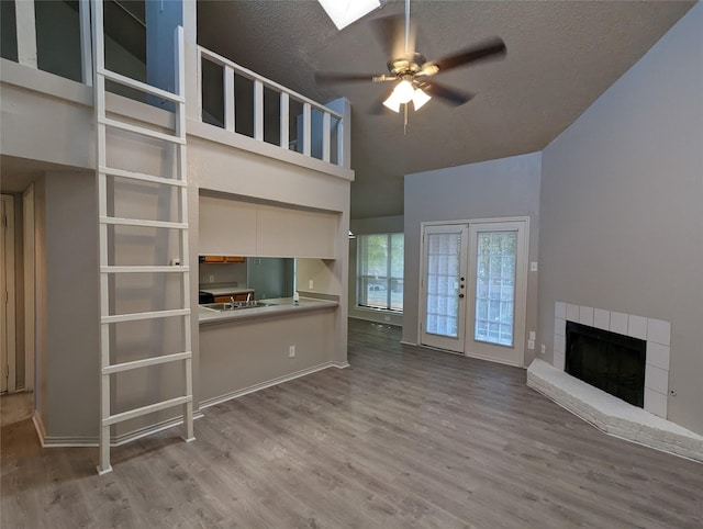 unfurnished living room featuring french doors, wood-type flooring, high vaulted ceiling, a textured ceiling, and ceiling fan