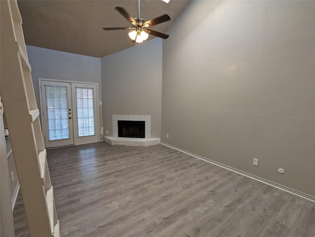 unfurnished living room featuring a tile fireplace, a textured ceiling, light wood-type flooring, and french doors