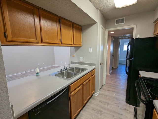 kitchen featuring light hardwood / wood-style floors, sink, a textured ceiling, and black appliances