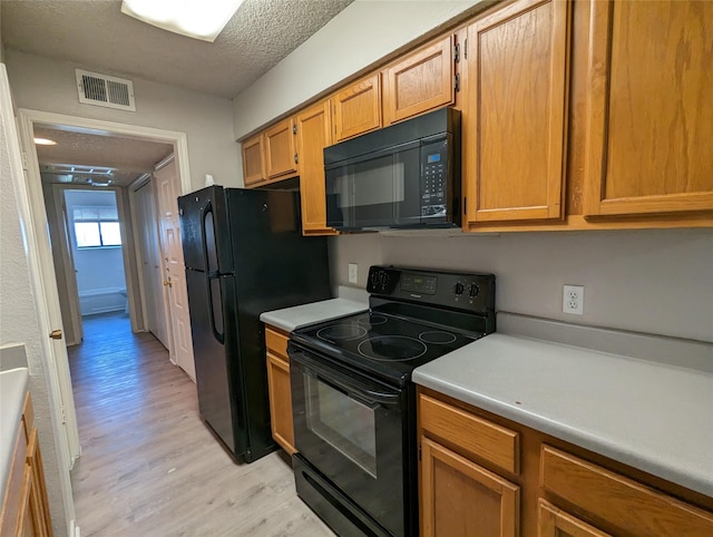 kitchen featuring light hardwood / wood-style flooring, a textured ceiling, and black appliances