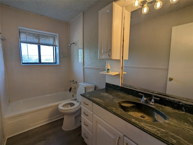 full bathroom with hardwood / wood-style floors, vanity, a textured ceiling, toilet, and tiled shower / bath