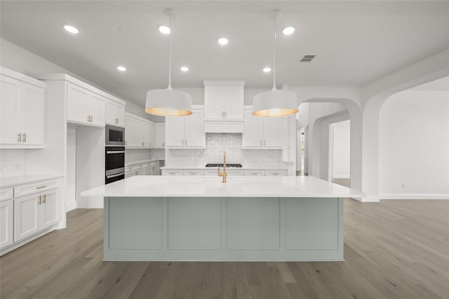 2301 Hawk Meadow Ct, Mansfield, TX 76063 - kitchen with stainless steel appliances, light wood finished floors, light countertops, tasteful backsplash, and white cabinets