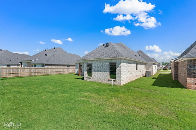 rear view of property featuring central AC unit and a yard