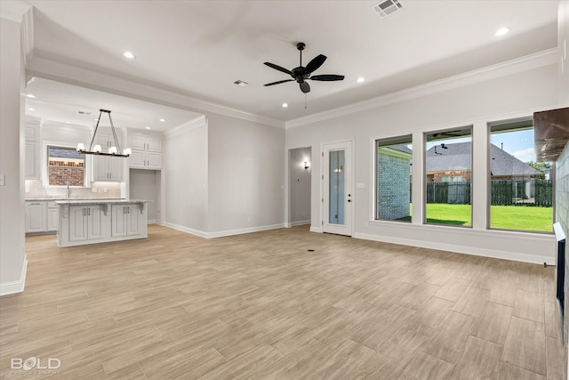 unfurnished living room featuring crown molding, sink, ceiling fan with notable chandelier, and light hardwood / wood-style flooring