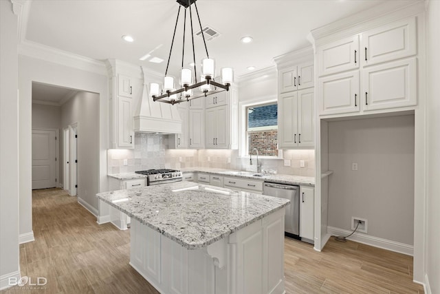 kitchen with a kitchen island, appliances with stainless steel finishes, white cabinetry, hanging light fixtures, and custom exhaust hood