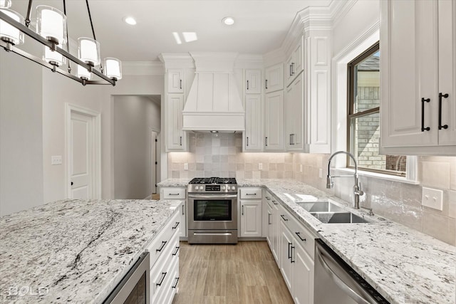 kitchen featuring sink, appliances with stainless steel finishes, white cabinets, decorative light fixtures, and custom exhaust hood