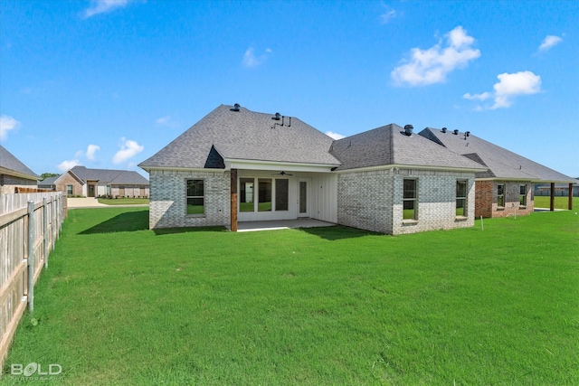 rear view of house with ceiling fan, a patio area, and a lawn