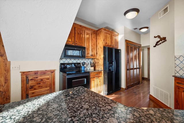 kitchen featuring tasteful backsplash, dark hardwood / wood-style flooring, dark stone counters, and black appliances