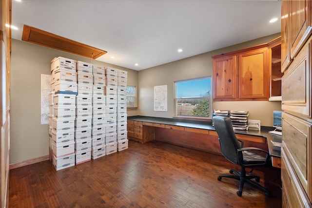 home office with dark wood-type flooring and built in desk