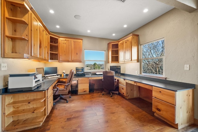 home office with built in desk and dark hardwood / wood-style flooring