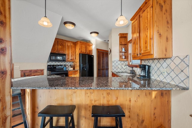 kitchen featuring a breakfast bar area, black appliances, and kitchen peninsula