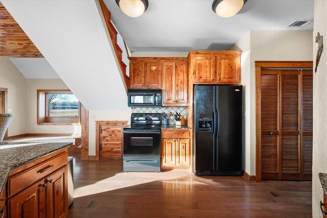 kitchen featuring dark wood-type flooring, dark stone countertops, hanging light fixtures, backsplash, and a wealth of natural light