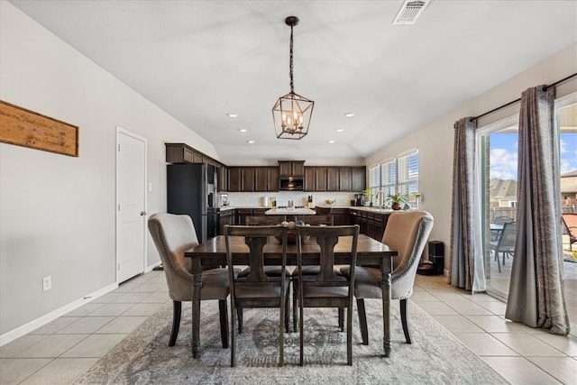 dining space with a notable chandelier, vaulted ceiling, and light tile patterned flooring