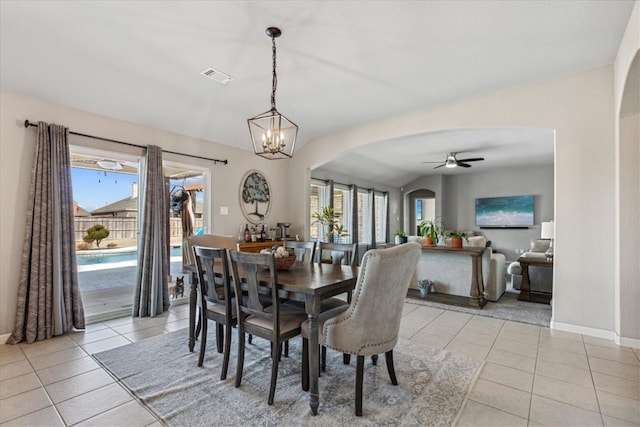 dining space with light tile patterned flooring, a healthy amount of sunlight, and ceiling fan with notable chandelier