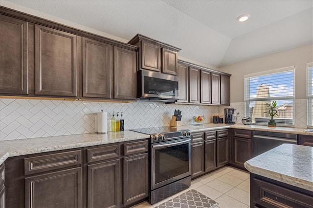 kitchen with light tile patterned flooring, dark brown cabinetry, lofted ceiling, tasteful backsplash, and appliances with stainless steel finishes