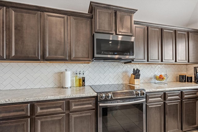 kitchen featuring tasteful backsplash, appliances with stainless steel finishes, light stone countertops, and dark brown cabinets