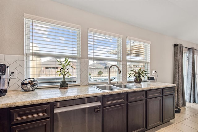 kitchen featuring dark brown cabinetry, dishwasher, sink, and light stone countertops