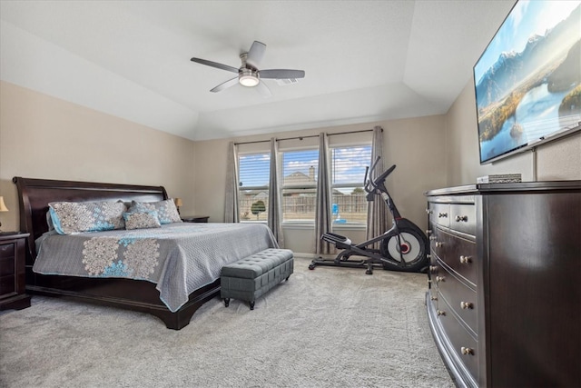 bedroom with lofted ceiling, light carpet, ceiling fan, and a tray ceiling