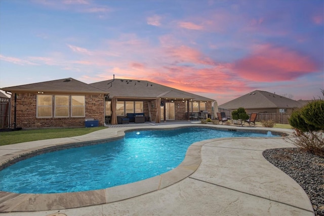 pool at dusk featuring a patio