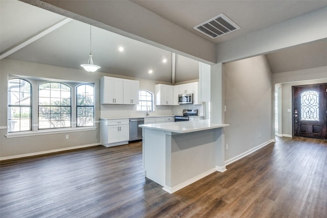 kitchen featuring lofted ceiling, sink, appliances with stainless steel finishes, white cabinetry, and hanging light fixtures