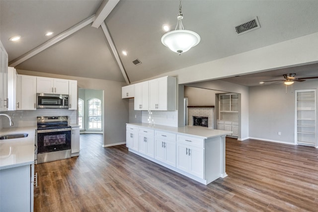 kitchen featuring stainless steel appliances, sink, white cabinets, and decorative light fixtures