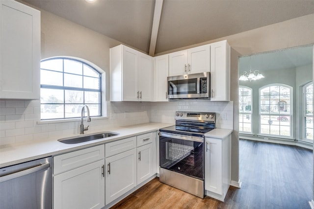 kitchen with white cabinetry, sink, lofted ceiling with beams, and appliances with stainless steel finishes