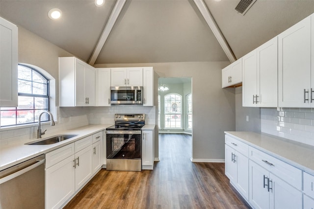 kitchen featuring sink, white cabinetry, lofted ceiling with beams, dark hardwood / wood-style flooring, and stainless steel appliances