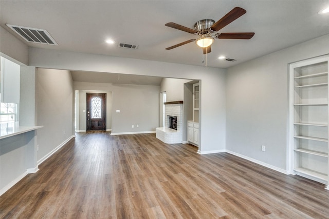 unfurnished living room featuring wood-type flooring, built in features, and a fireplace