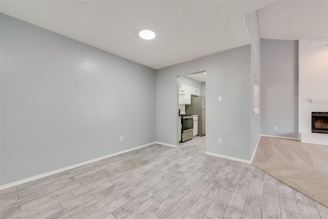 unfurnished living room with a brick fireplace and light wood-type flooring