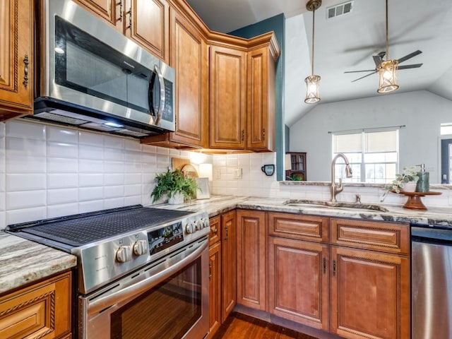 kitchen featuring vaulted ceiling, appliances with stainless steel finishes, sink, backsplash, and light stone counters