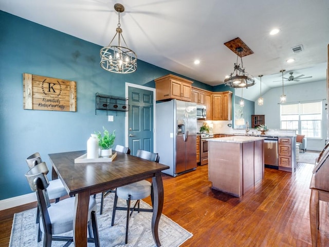 kitchen with stainless steel appliances, decorative light fixtures, kitchen peninsula, and a kitchen island