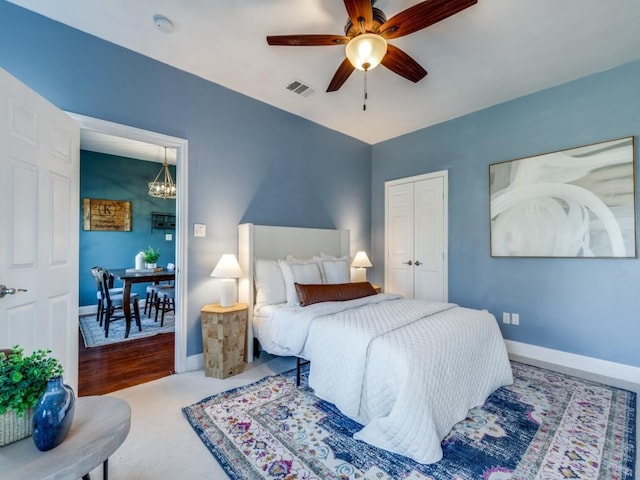 bedroom with carpet, ceiling fan with notable chandelier, and a closet