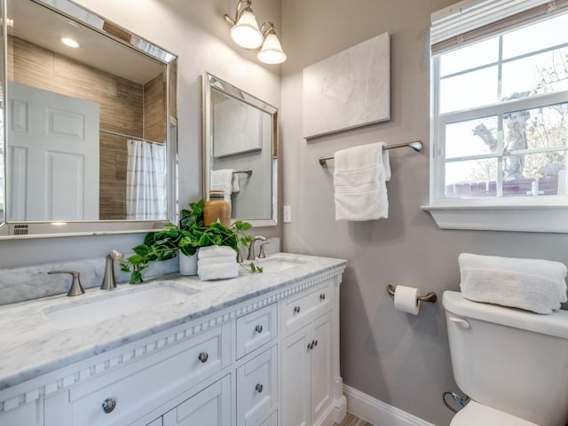 bathroom with vanity, curtained shower, toilet, and a healthy amount of sunlight