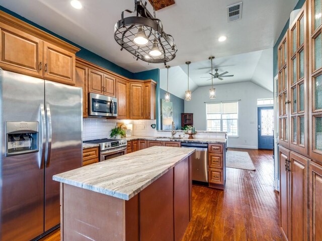 kitchen with stainless steel appliances, a kitchen island, kitchen peninsula, and hanging light fixtures