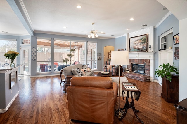 living room featuring dark wood-type flooring, a fireplace, built in features, and crown molding